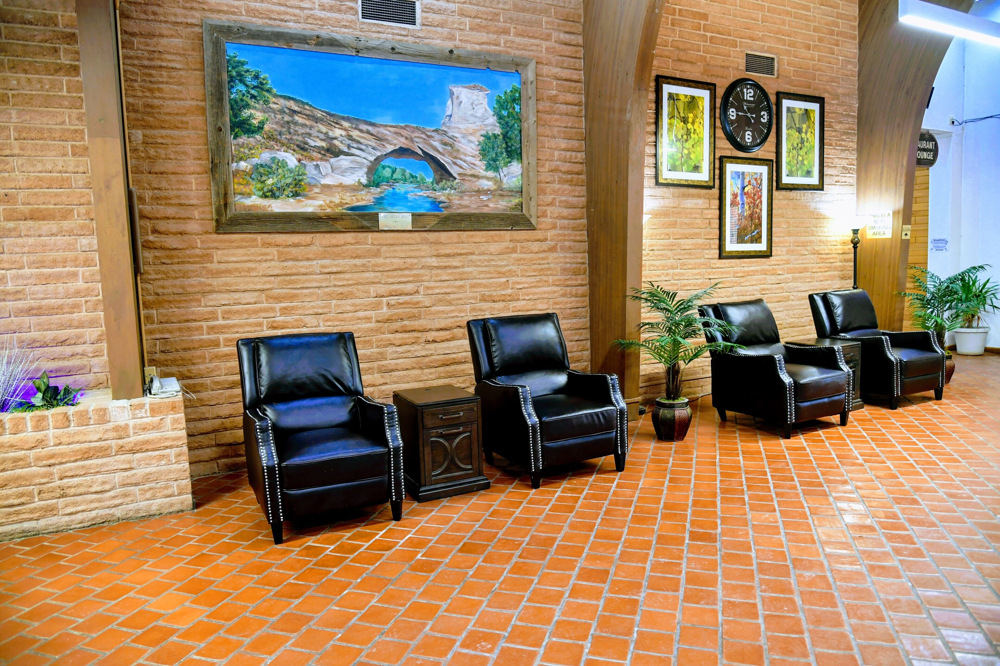 A lobby with brick walls, a mural of a bridge, and black leather chairs.