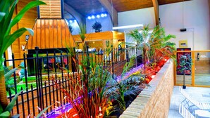A modern indoor space with a brick fireplace, wooden ceiling, and a variety of indoor plants. - Douglas Inn & Conference Center (Douglas)