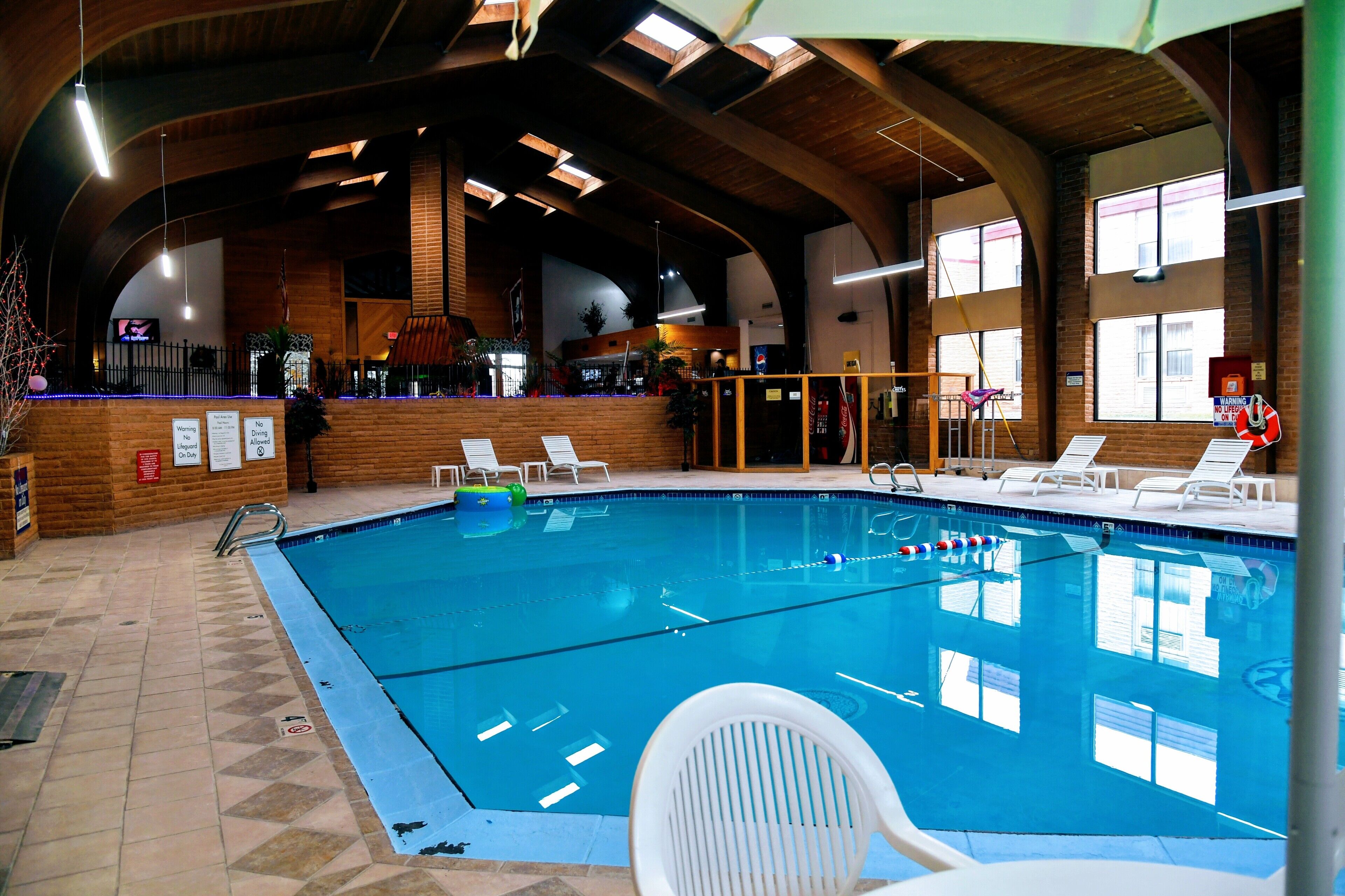 An indoor swimming pool with clear water, surrounded by lounge chairs and a wooden interior.