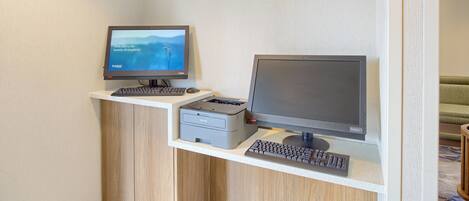 A reception desk with a computer monitor, printer, and keyboard. The wall has a sign that reads "Connect & Print".