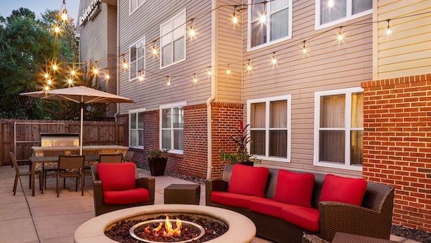 A patio area with a fire pit, outdoor furniture, and string lights.