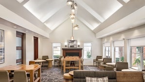 A spacious room with a high ceiling, a fireplace, a dining area, and seating arrangements.
