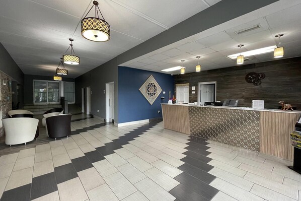 A reception area with a check-in counter, seating area with chairs, and patterned ceiling lights.