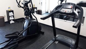 A gym with treadmills, elliptical machines, and a bench. There are weights and a water bottle on the floor. - Econo Lodge Forest City (Forest City)