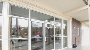 A building entrance with large glass doors, a brick wall, and a concrete floor. - Econo Lodge Forest City (Forest City)