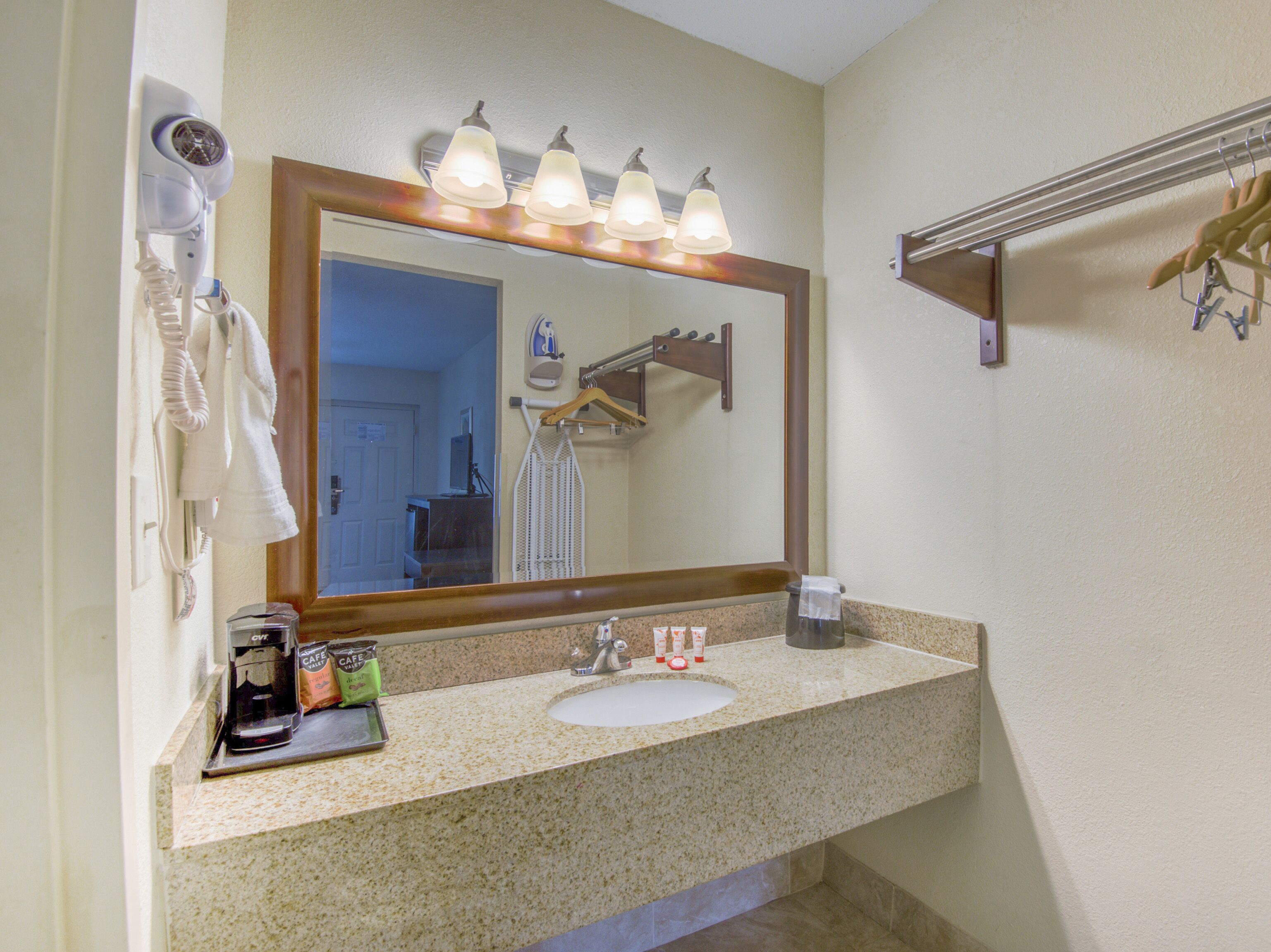 A bathroom with a sink, mirror, and towel rack.