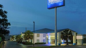 Un hôtel Travelodge avec une enseigne, un parking et un bâtiment doté d’un toit bleu.