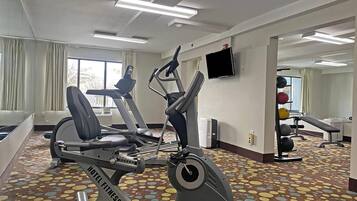 Een hotel fitnessruimte met trainingsapparatuur, een televisie en een kamerbreed tapijt met dessin.