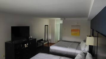 A hotel room with two beds, a TV, a dresser, and a painting on the wall.