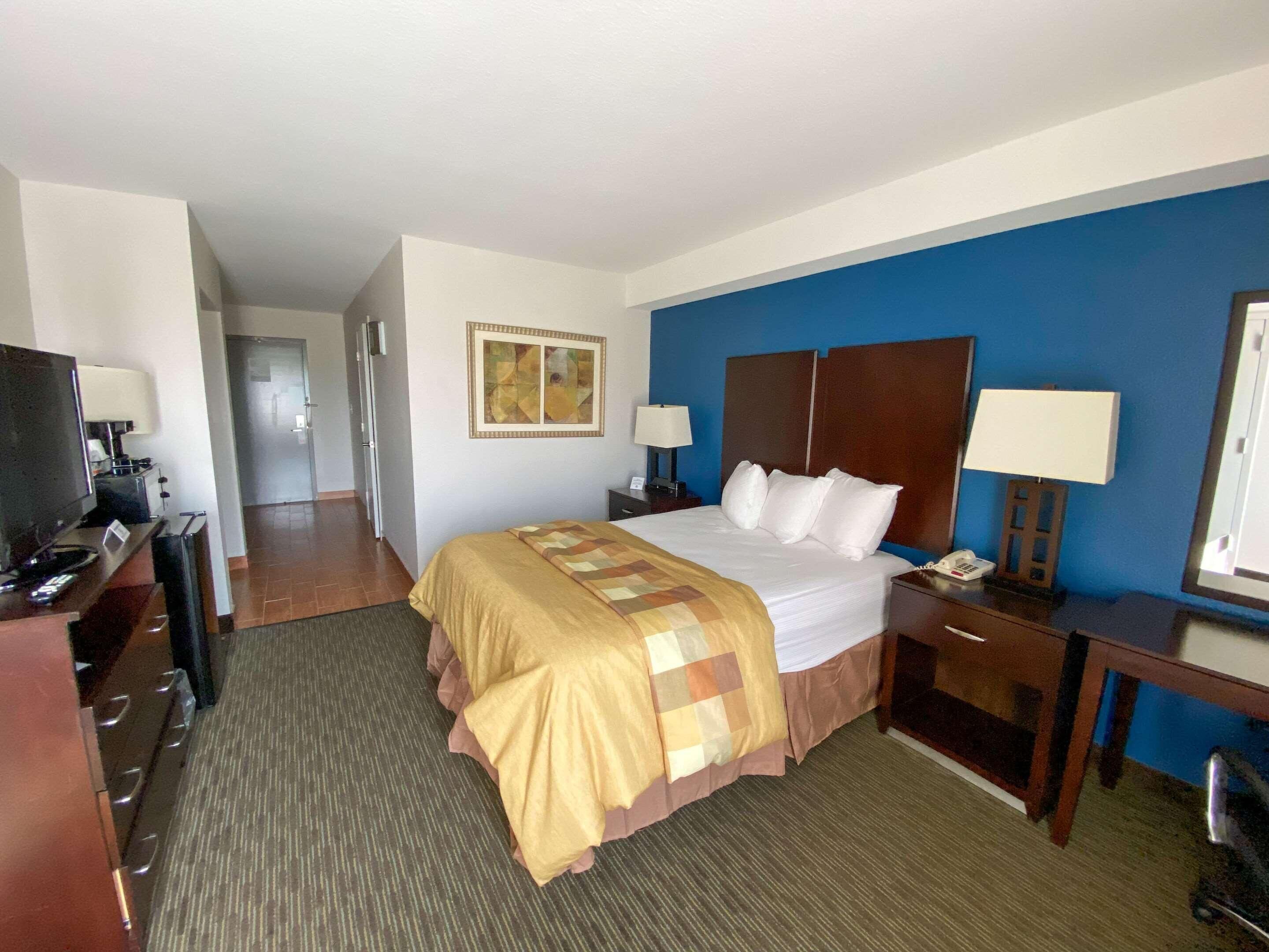 Ein Hotelzimmer mit Bett, Schreibtisch mit Computer, Fernseher, Telefon und Lampe.
