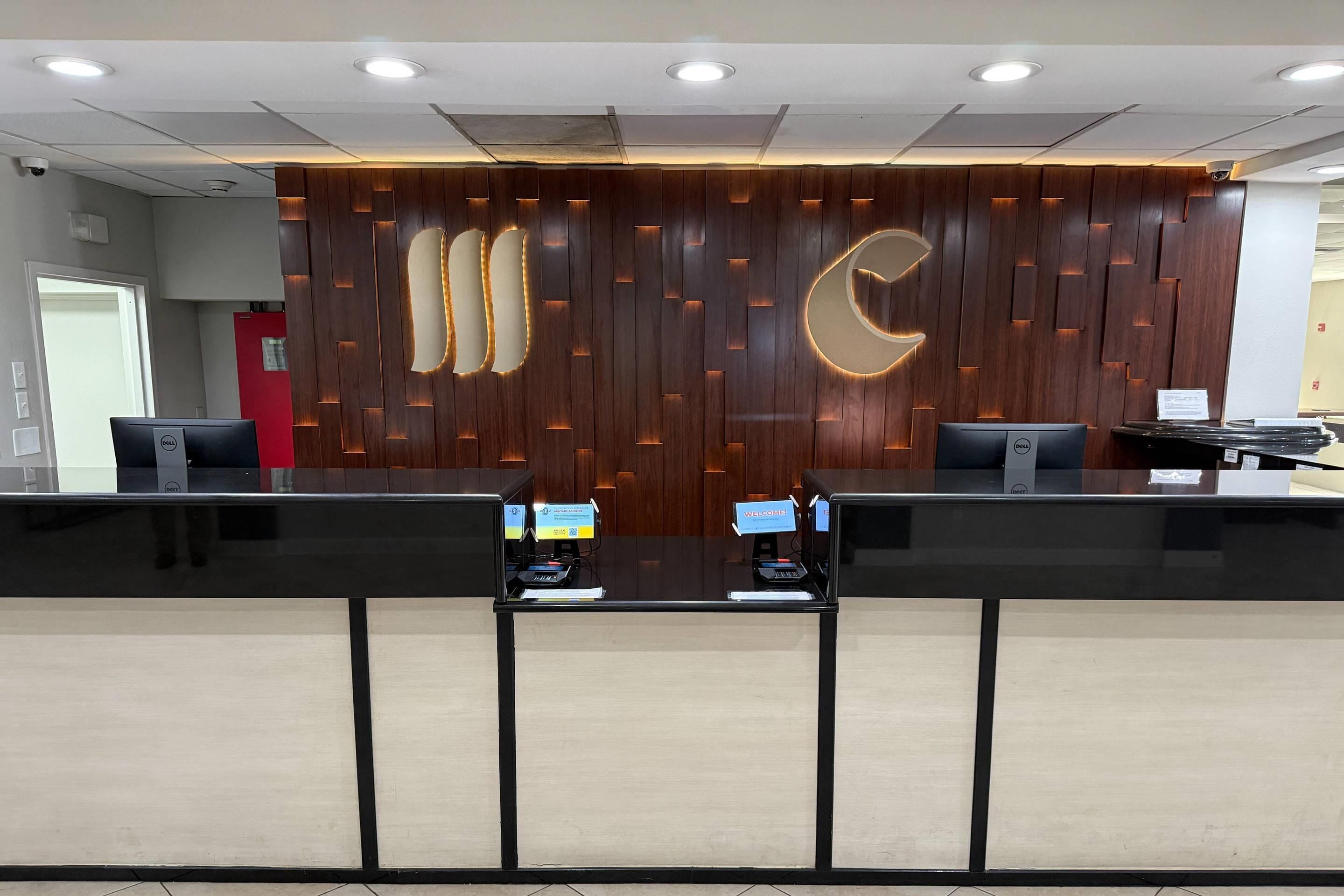 A reception desk with a wooden panel design, two computer monitors, and a crescent moon motif.
