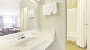 A hotel bathroom with a large mirror, a white sink, and a shower area. - Super 8 by Wyndham Shelby (Shelby)