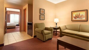 A hotel room with a bed, a green armchair, a sofa, a small table with a lamp, and two framed pictures on the wall. - Days Inn by Wyndham Swift Current (Swift Current)
