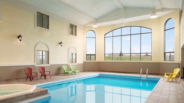 An indoor swimming pool with clear blue water, surrounded by tiled walls and large arched windows. - Days Inn by Wyndham Swift Current (Swift Current)