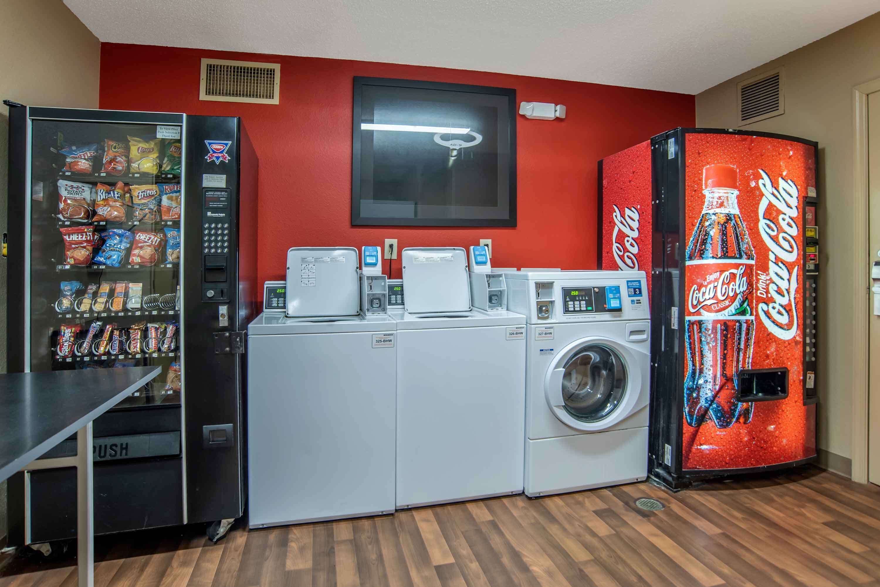 Zona de lavandería con máquina expendedora, lavadora y secadora.