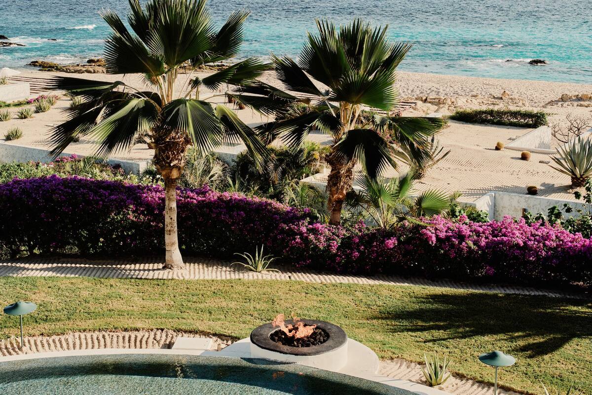 A pool area with a circular design, palm trees, and a view of the beach.
