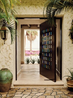 A doorway with a stained glass panel, a palm tree, and a tiled floor.