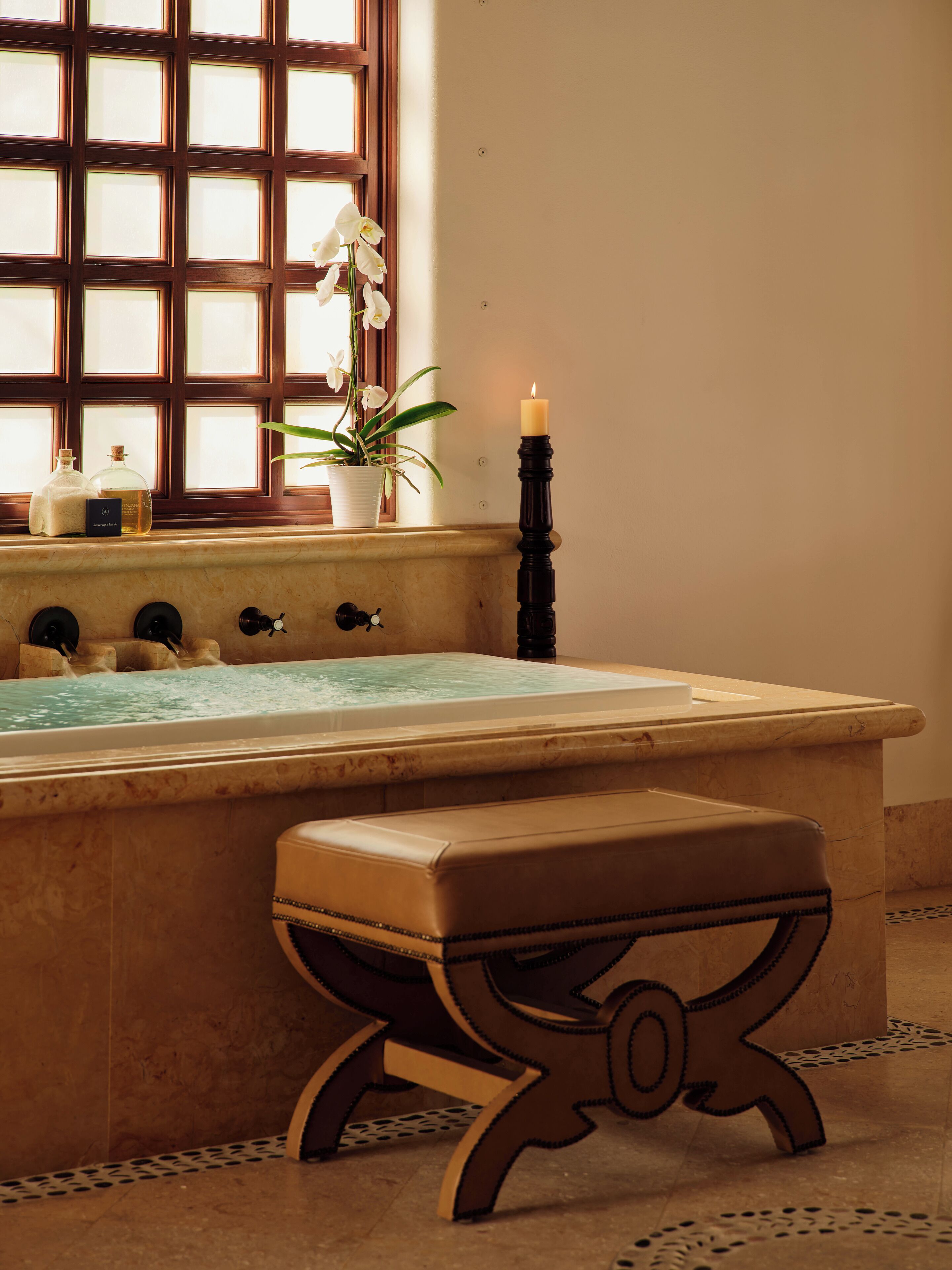 A bathroom with a bathtub, a window with a view, a candle, and a potted plant.