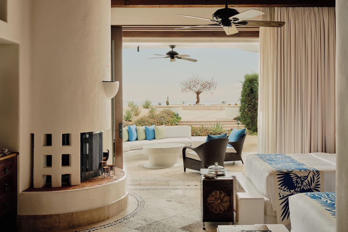 A room with a ceiling fan, a view of the beach, a sofa, and a dining table.