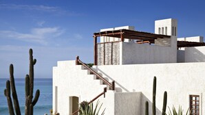 A white building with a staircase leading to a covered area, surrounded by cacti and aloe plants, overlooking the sea. - Las Ventanas al Paraiso, A Rosewood Resort (San José del Cabo)