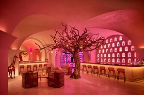 A bar area with a central tree, bar stools, and a wine rack in the background.