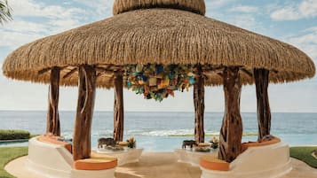 A thatched-roof gazebo with a view of the ocean.