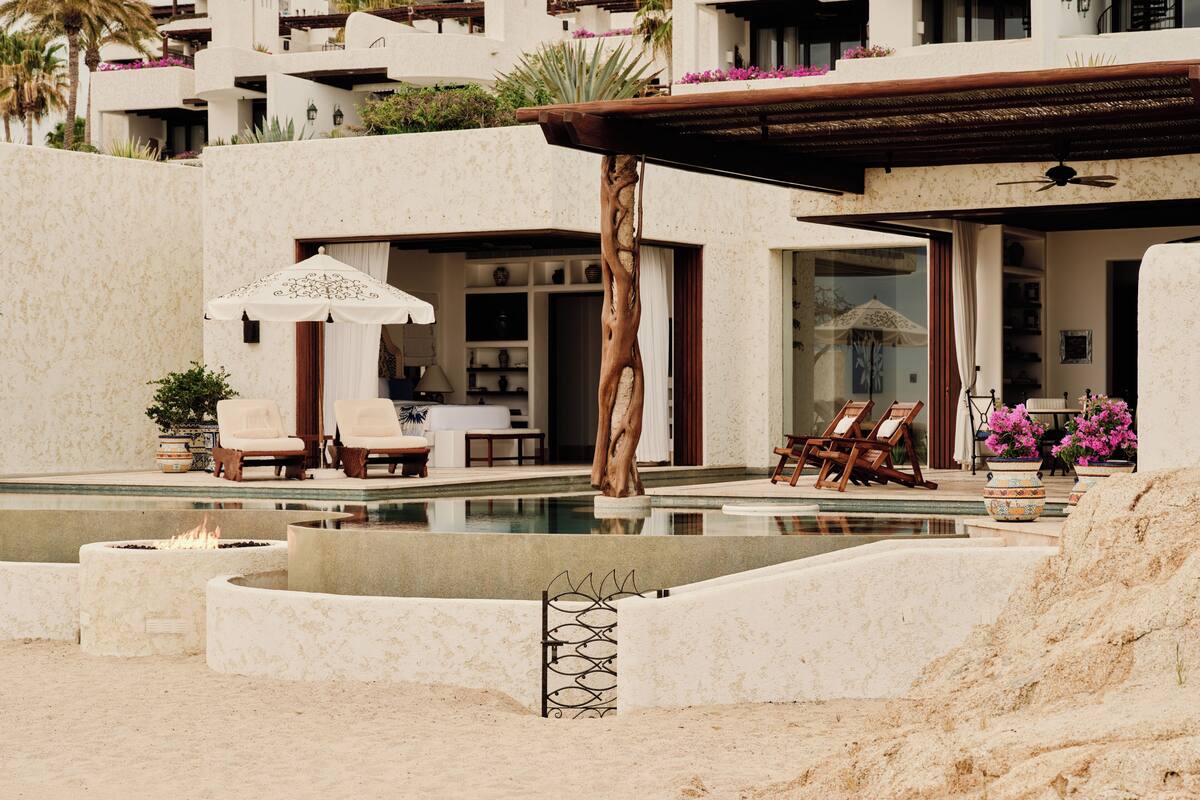 A pool area with lounge chairs, a pergola, and a view of a residential building with balconies.