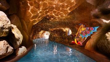Relax by the serene pool surrounded by natural rock formations and a vibrant mural.