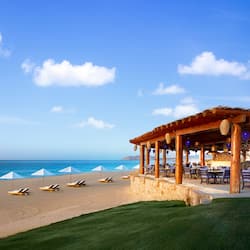 Enjoy ocean views from the covered outdoor dining area with tables and chairs.