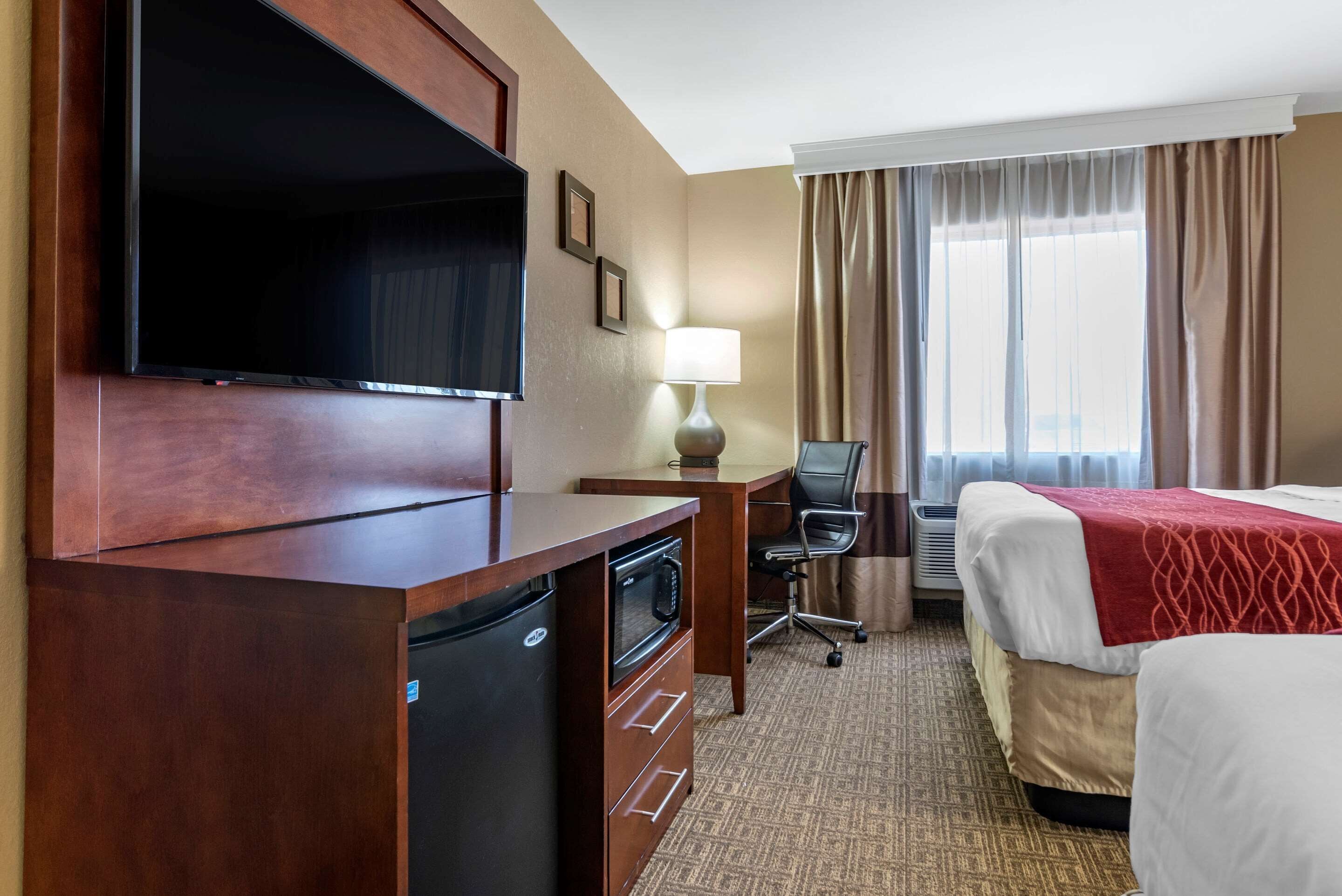 Habitación de hotel con televisión, escritorio, silla y dos camas.