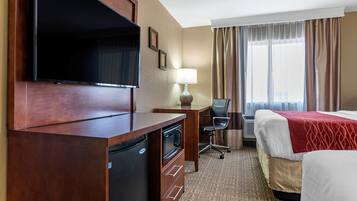 Habitación de hotel con televisión, escritorio, silla y dos camas.