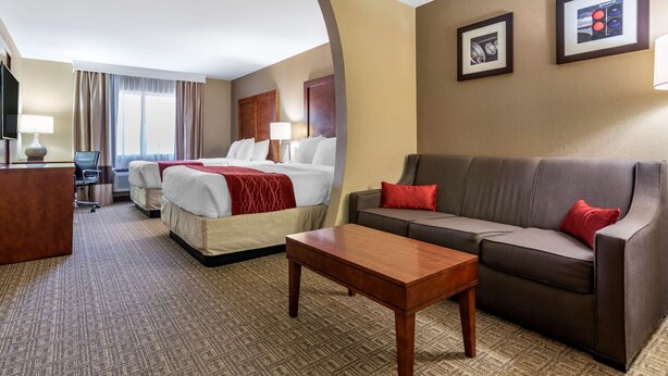 A hotel room with a bed, two bedside tables, a sofa, a desk, and a television. - Comfort Inn & Suites Leeds I-20 (Leeds)