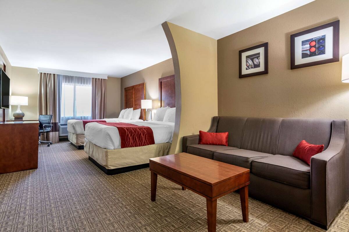A hotel room with a bed, two bedside tables, a sofa, a desk, and a television.