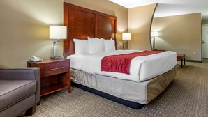 A hotel room with a large bed, two bedside tables, a desk, a chair, and a mirror. - Comfort Inn & Suites Leeds I-20 (Leeds)