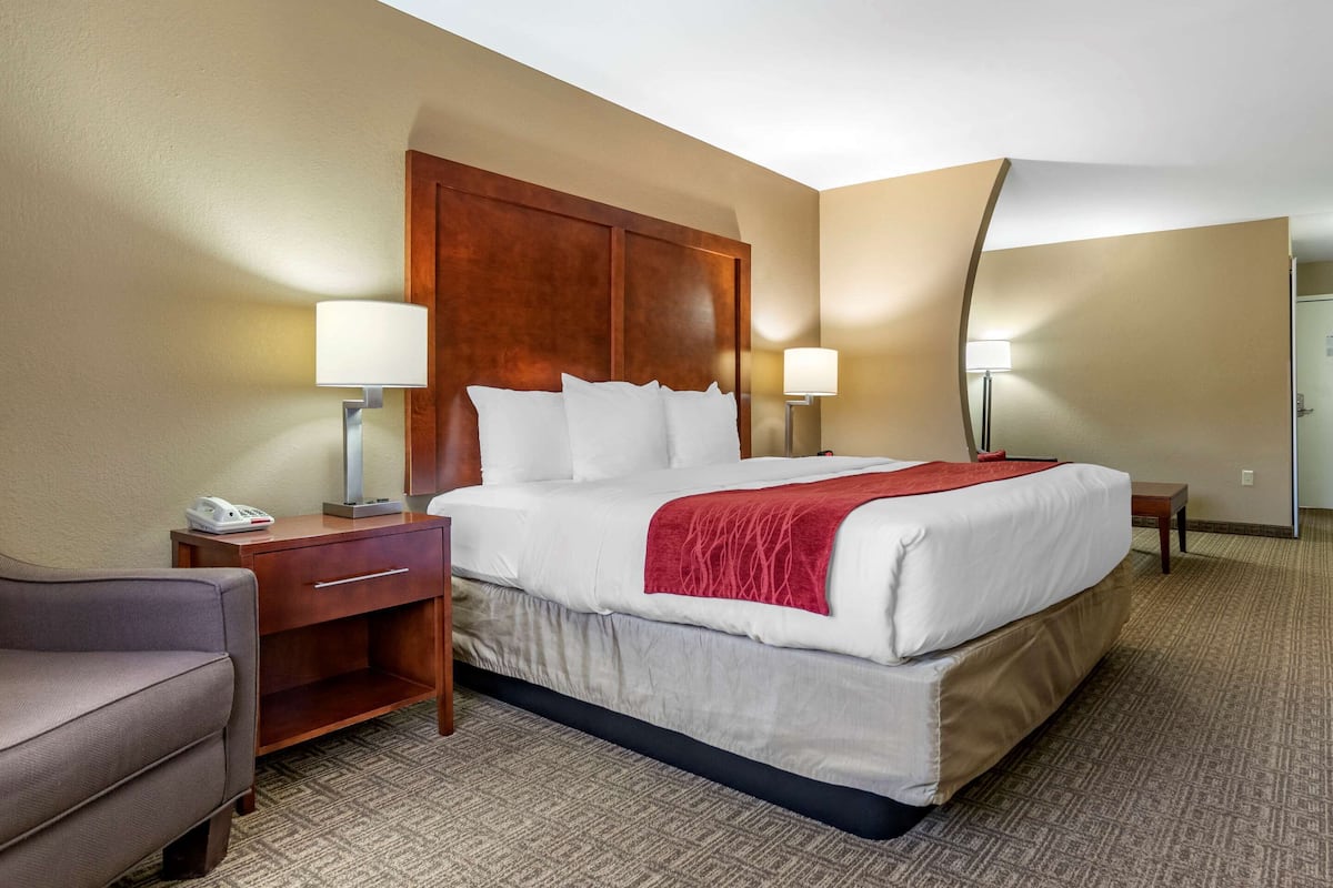 A hotel room with a large bed, two bedside tables, a desk, a chair, and a mirror.