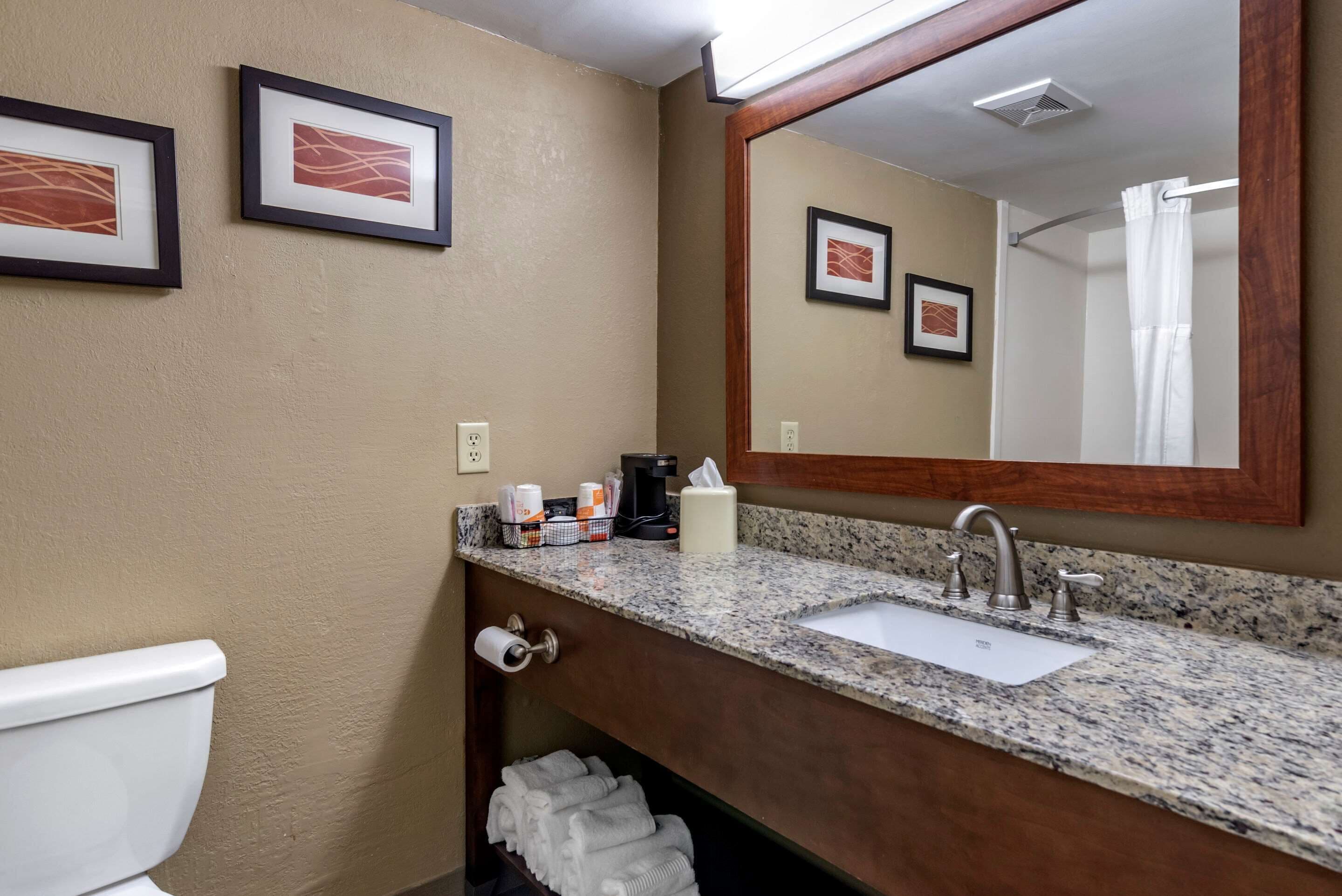 A bathroom with a sink, mirror, toilet, and towel rack.
