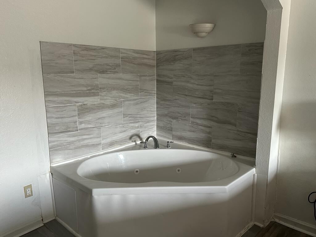 Un baño moderno con una bañera independiente, paredes con diseño de mármol y un aplique de pared.