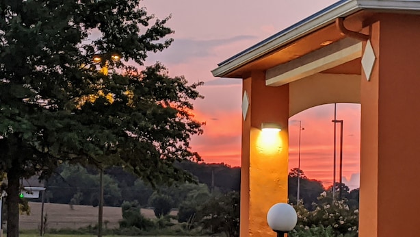 A sunset view through a building's archway, with trees and a field in the background. - Quality Inn & Suites Decatur - Priceville I-65 (Decatur)