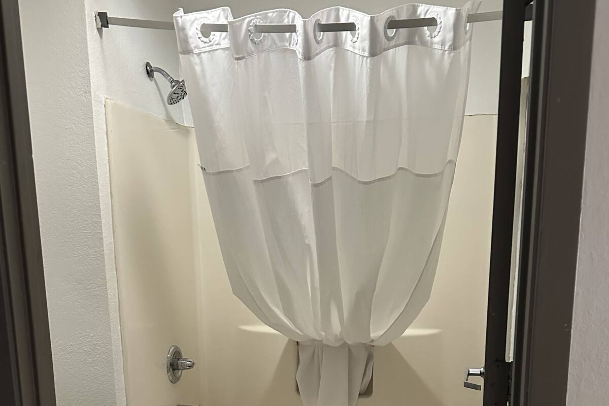 A bathroom with a bathtub, toilet, and a shower curtain.