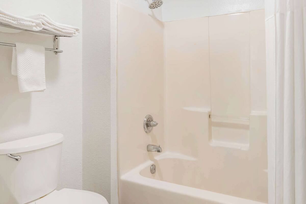 A bathroom with a toilet, a bathtub, and a towel rack with folded towels.