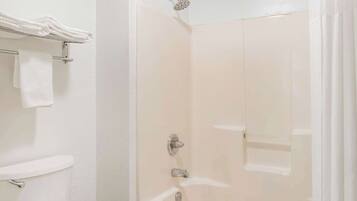 A bathroom with a toilet, a bathtub, and a towel rack with folded towels.