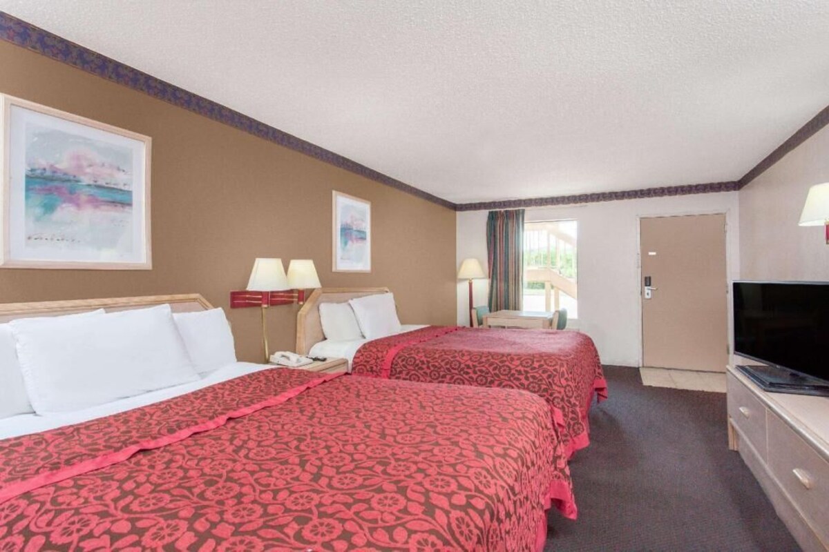 Une chambre d’hôtel avec deux lits, une télévision, un bureau et une porte.