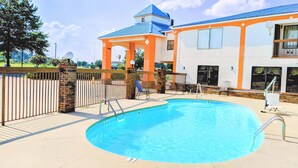 A swimming pool with a blue water feature, surrounded by a brick wall and a metal fence. - Quality Inn & Suites Decatur - Priceville I-65 (Decatur)