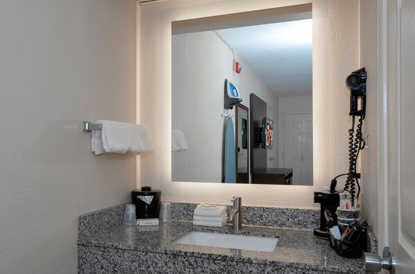 Ein Badezimmer mit Granitwaschtisch, Waschbecken, Spiegel und Handtuchhalter.