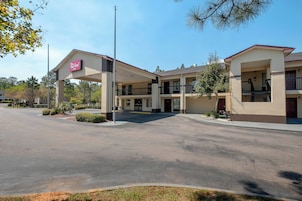 A Red Roof Inn with a two-story structure, a covered parking area, and a clear sky.