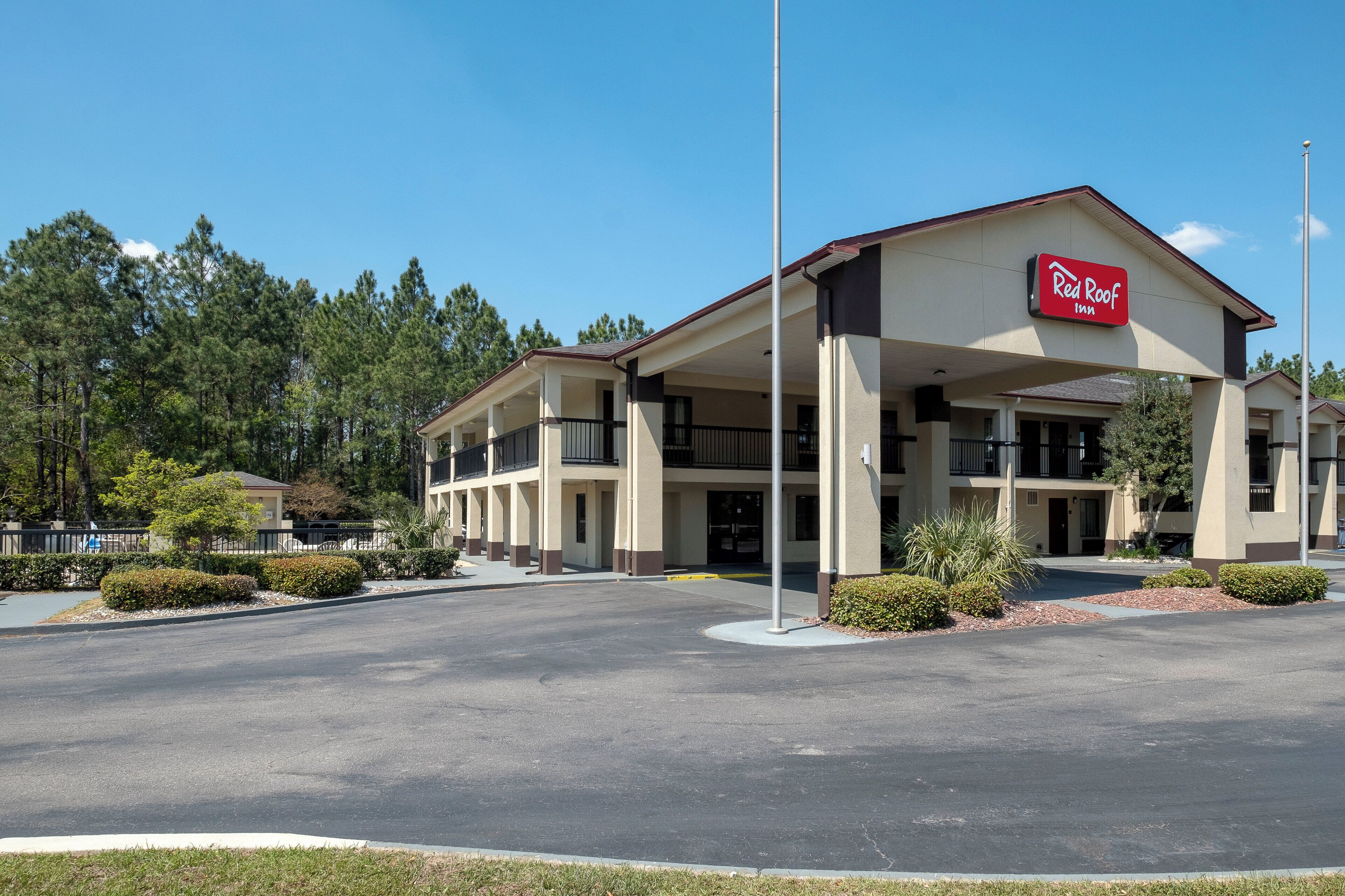 A Red Roof Inn with a two-story structure, a covered parking area, and a landscaped front yard.