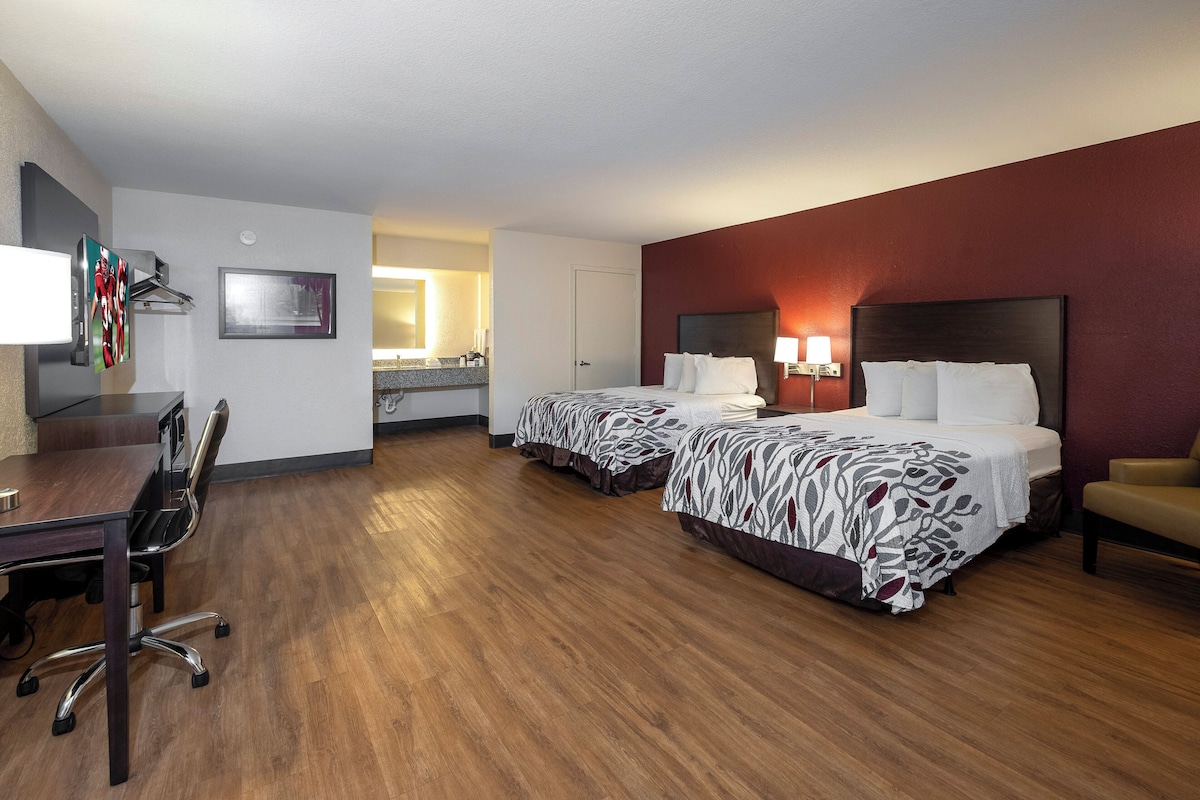 Een hotelkamer met twee bedden, een bureau, een stoel en een televisie.