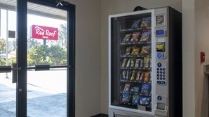 Ein Warenautomat voller Snacks, durch die Tür ist ein Schild des Red Roof Inn sichtbar.