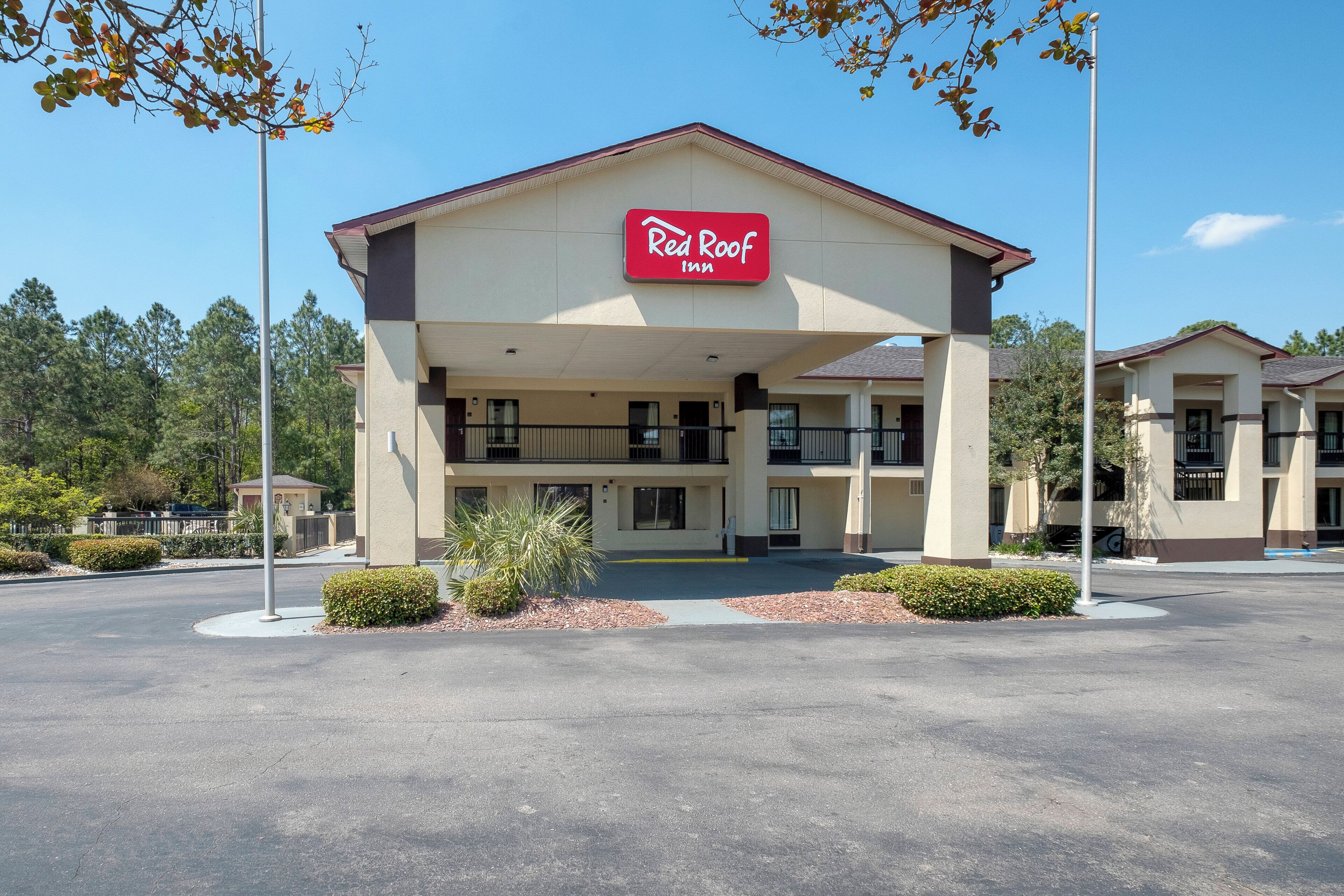 A Red Roof Inn with a two-story structure, a covered front porch, and a parking lot.