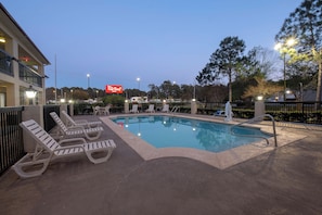 A swimming pool with lounge chairs and a Red Roof Inn sign in the background. - Red Roof Inn Gulf Shores (Gulf Shores)